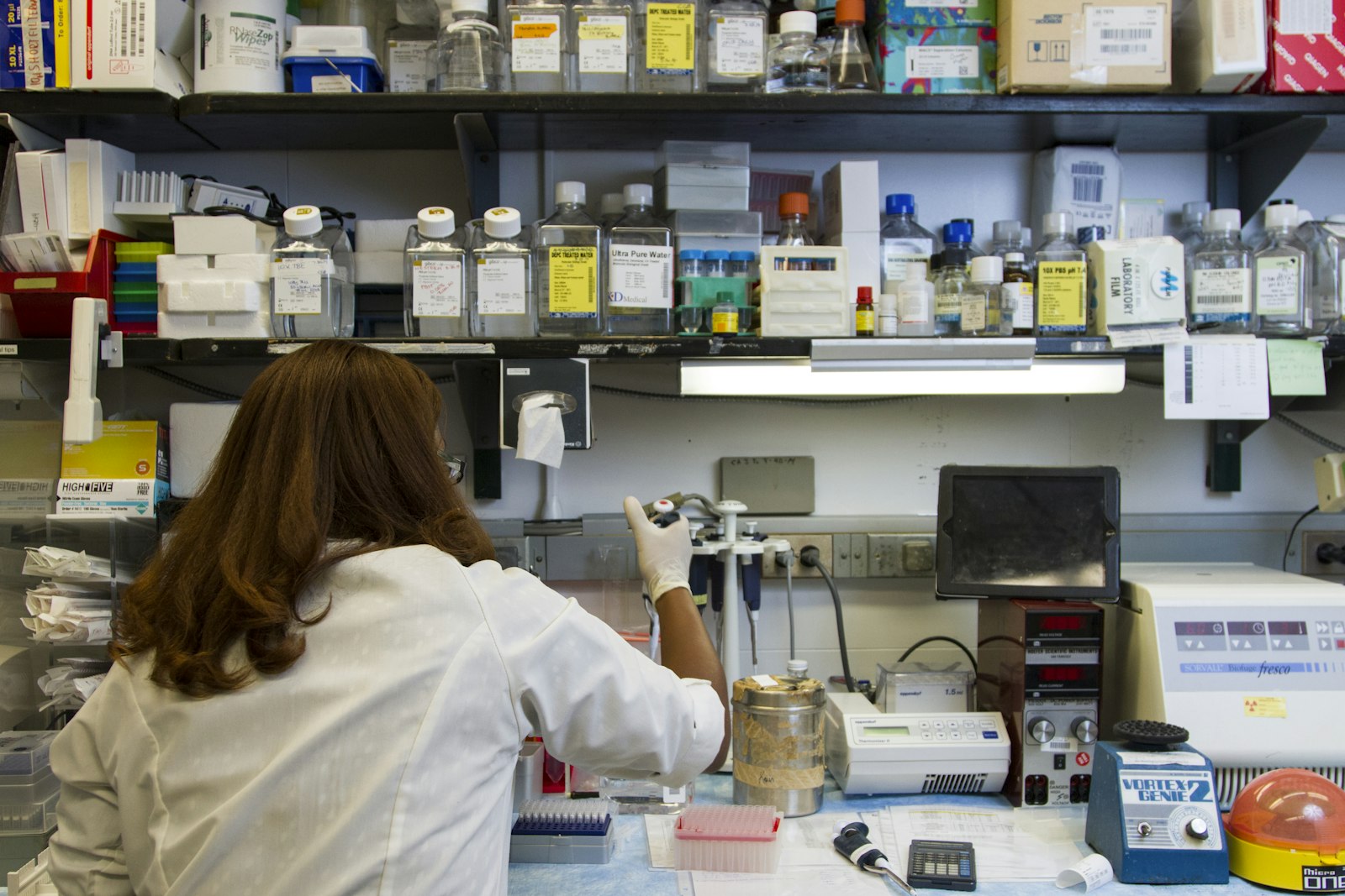 A scientist working at a laboratory bench surrounded by research equipment